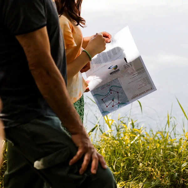 Dans « Je me laisse porter », deux personnes marchent dans les herbes hautes, une carte dépliée à la main.