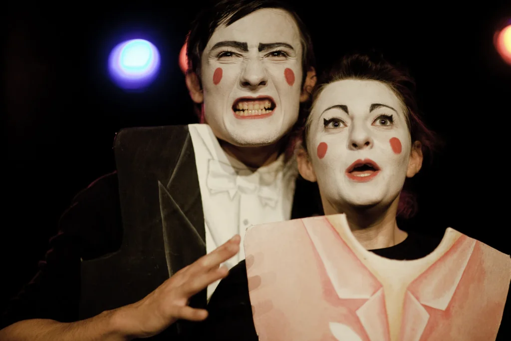 Dans « Circonférence », deux comédiens au visage maquillé de blanc, joues rouges, l’un grimaçant, l’autre bouche ouverte.